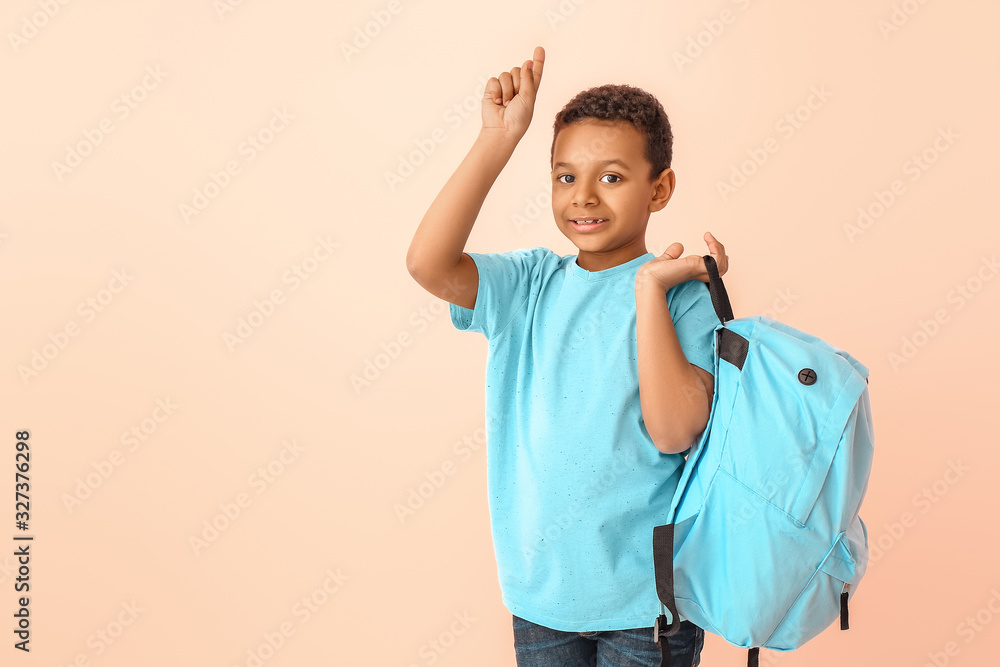 Cute African-American schoolboy with raised index finger on color background