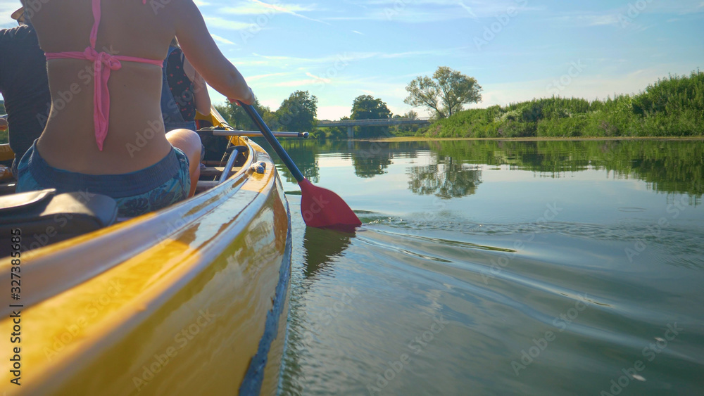 CLOSE UP: Young man and woman paddle a canoe down a calm river in Slovenia.