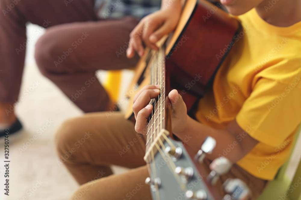 Little African-American boy playing guitar at music school