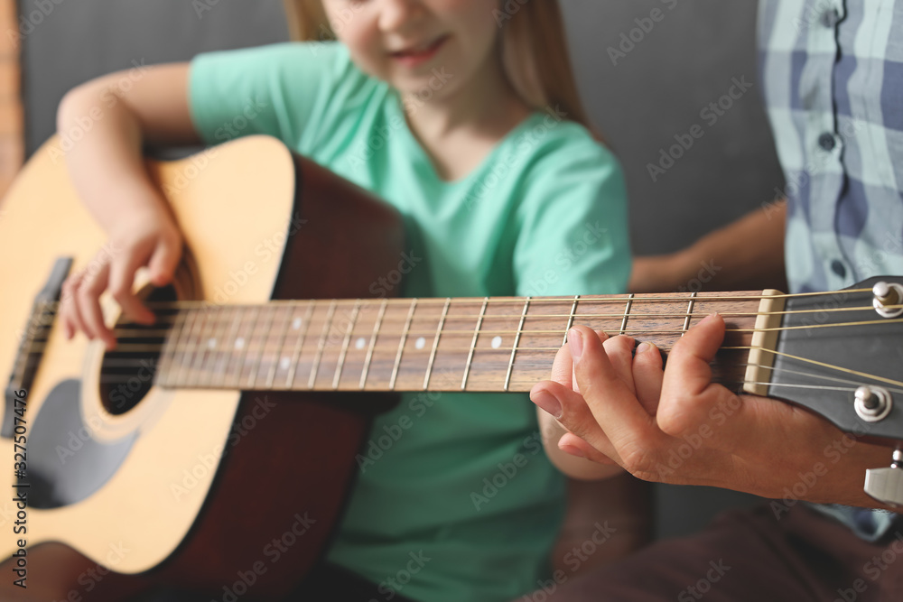 Little girl playing guitar at music school, closeup