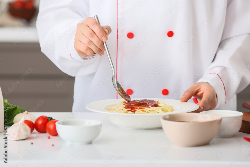 Female chef cooking tasty pasta with tomato sauce in kitchen, closeup