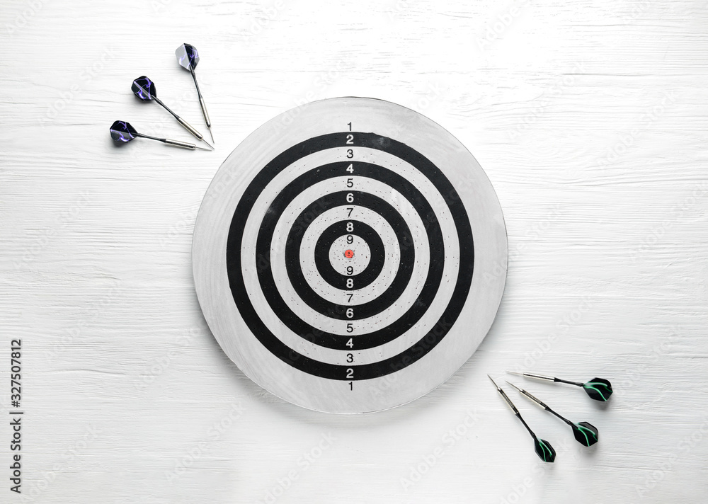 Dartboard with darts on white wooden background