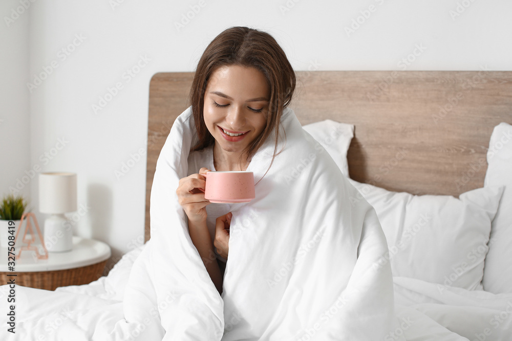 Morning of beautiful young woman drinking coffee in bed