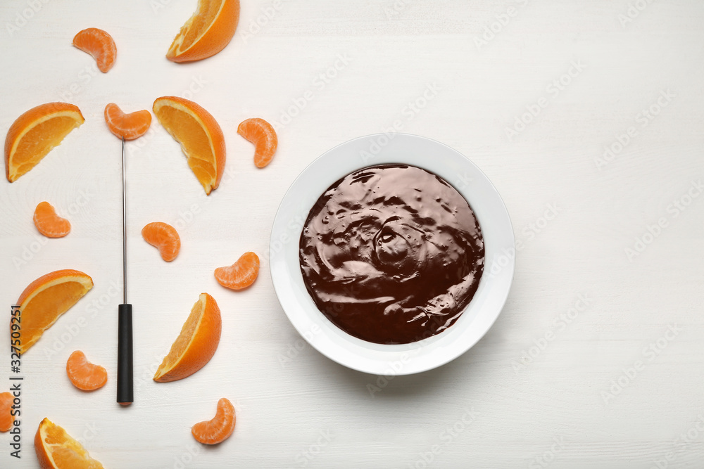 Bowl with tasty chocolate fondue and citrus fruits on white table