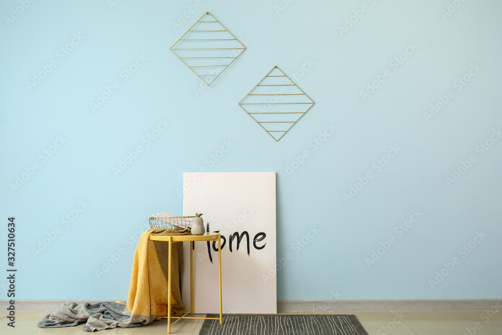 Table with plaid, books and decor near color wall in room