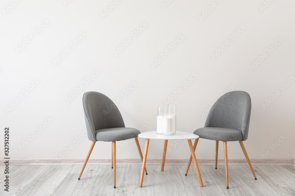 Chairs with table near white wall in room