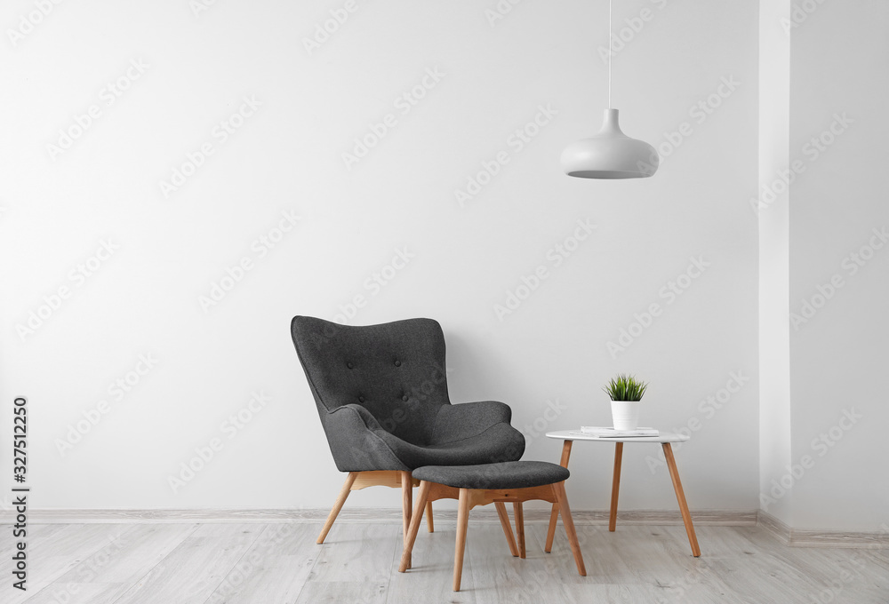 Interior of light room with armchair and table with houseplant