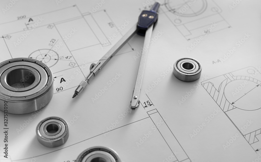 Bearings with pair of compasses and drawings on table of engineer