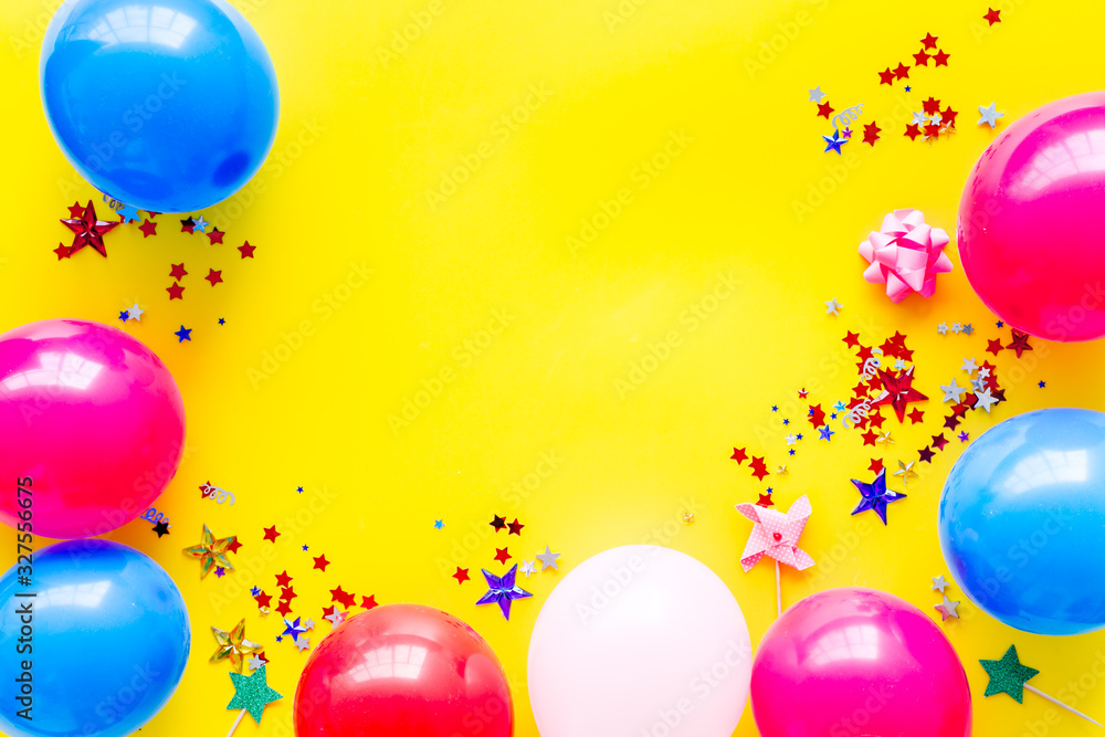 Party concept. Colorful balloons and confetti on yellow background top-down frame copy space