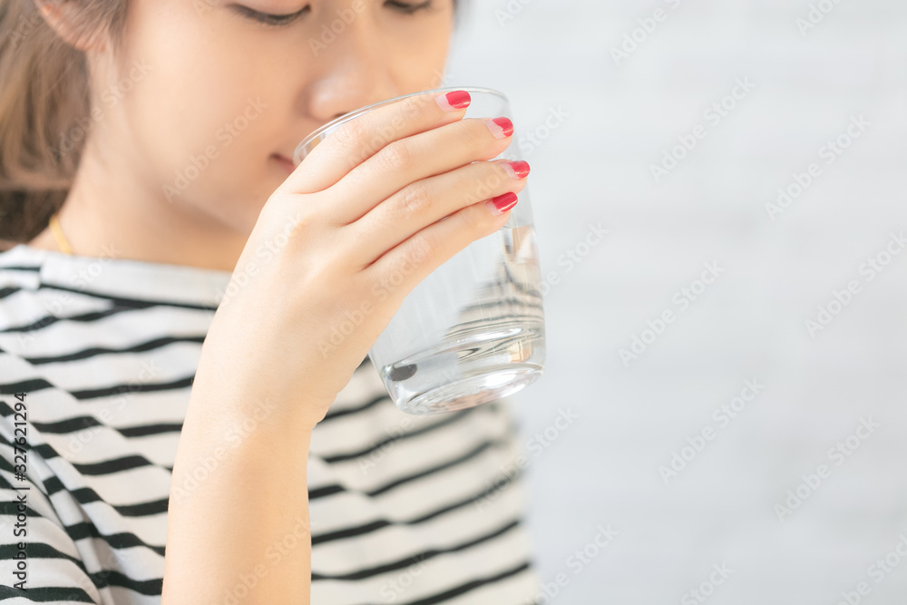 美丽的亚洲女人在喝水。特写镜头，专注于她的手臂。