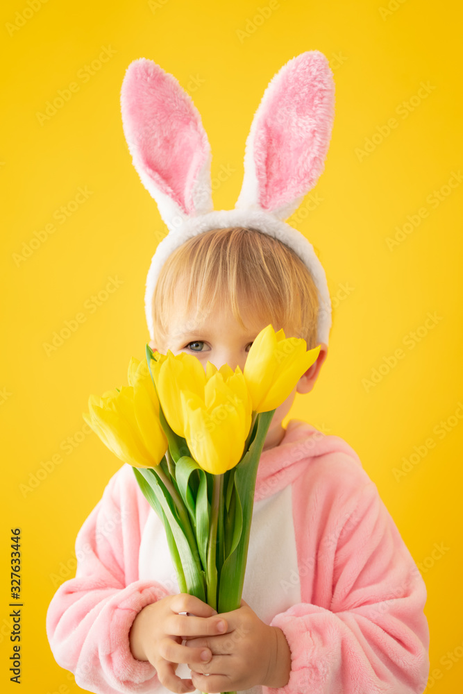 Funny kid wearing Easter bunny against yellow background