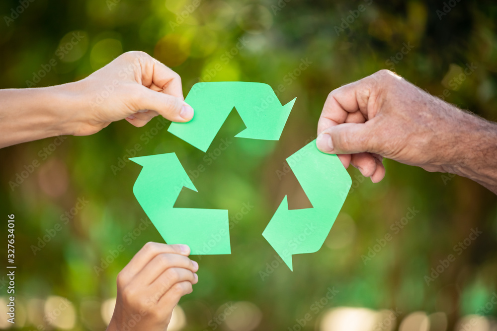 People holding recycle symbol against green spring background