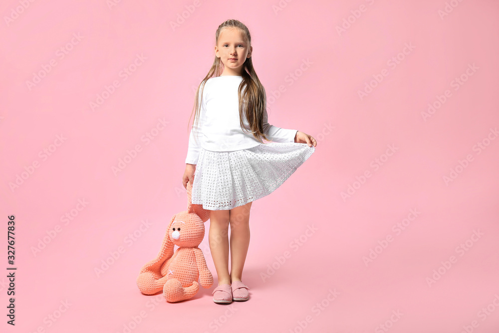 Cute little girl with toy on color background