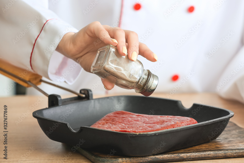 Female chef cooking meat in kitchen, closeup