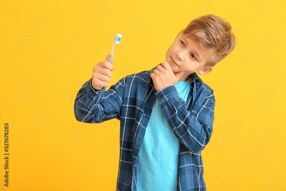 Cute little boy with toothbrush on color background