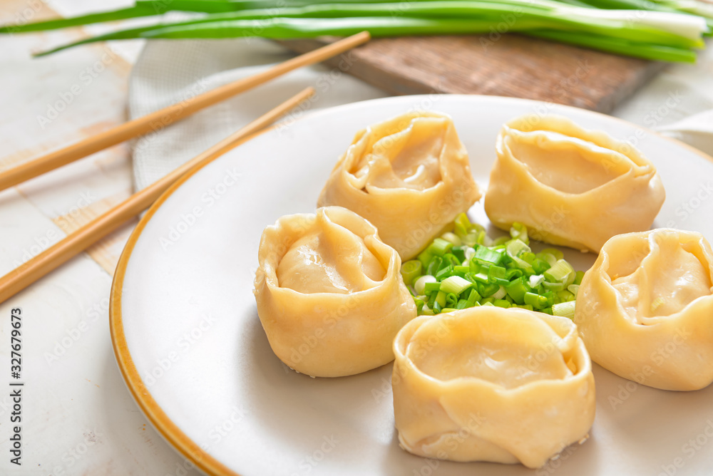 Plate with oriental dumplings and onion on table, closeup