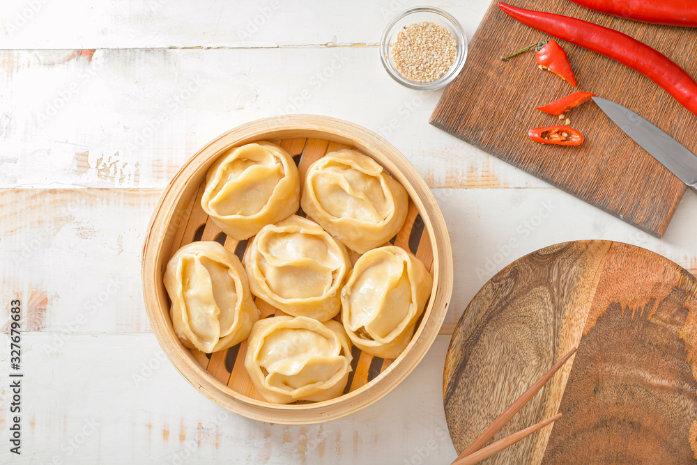 Steamer with oriental dumplings and chili pepper on table