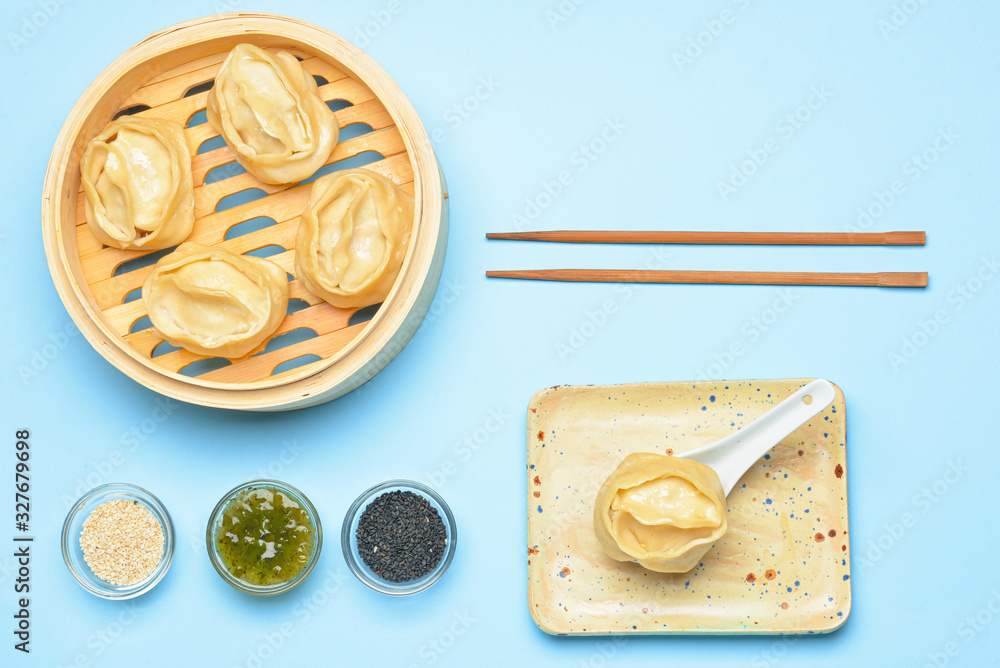 Steamer with oriental dumplings and sauce on color background