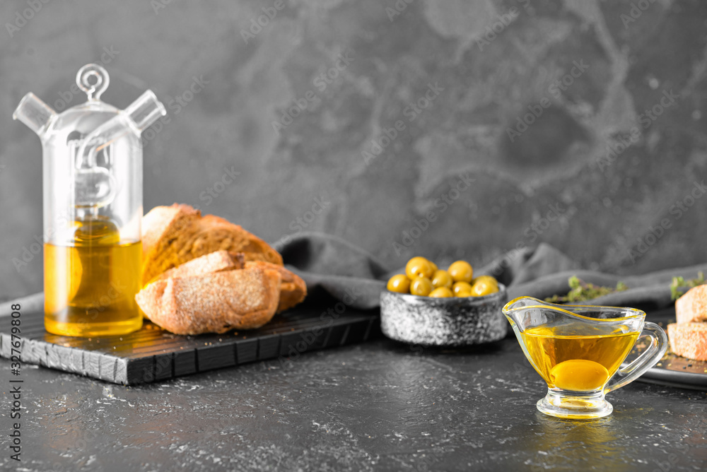 Tasty olive oil and bread on dark background