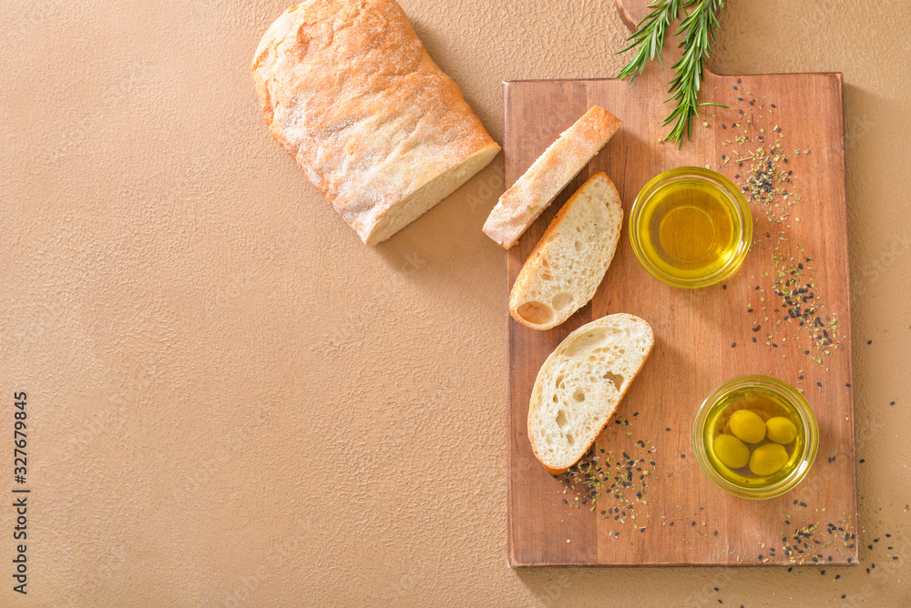 Tasty olive oil with bread on color background