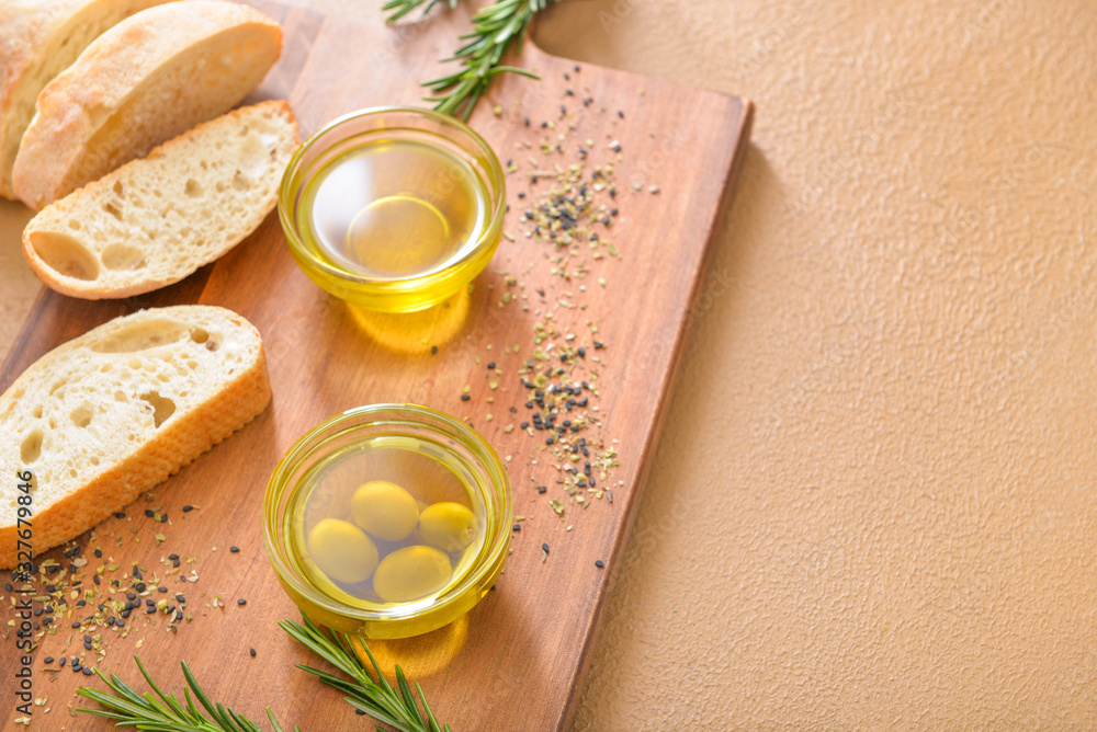 Tasty olive oil with bread on color background