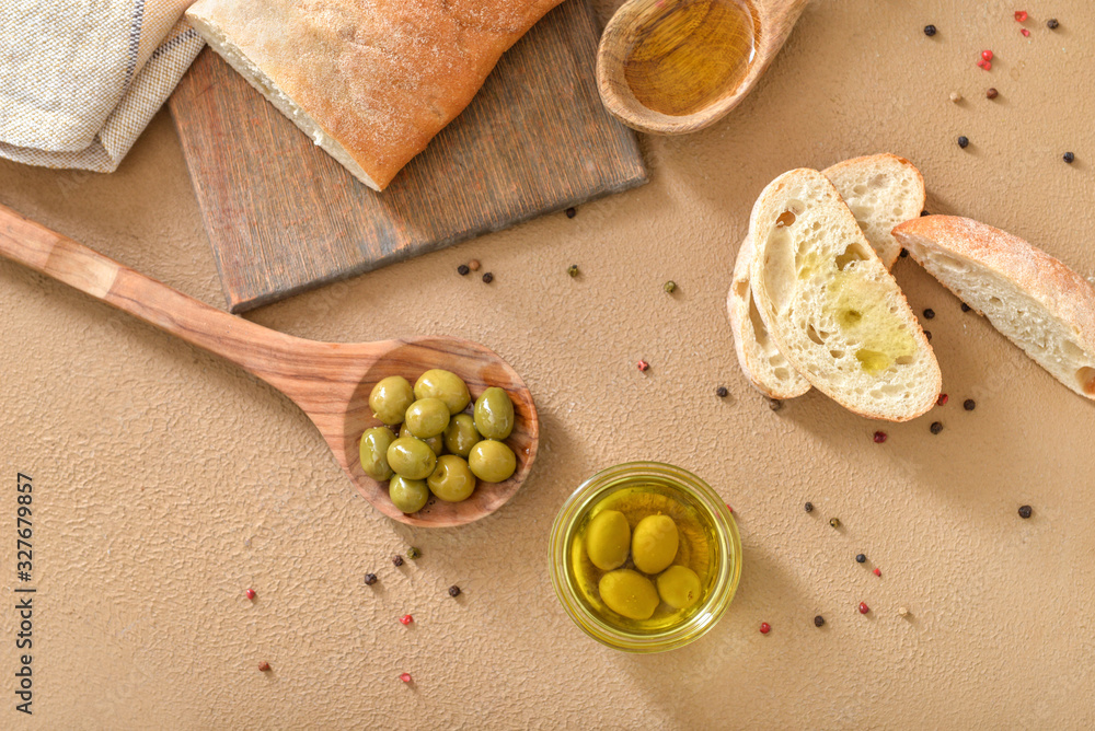 Tasty olive oil with bread on color background