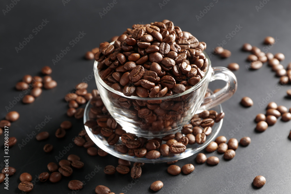 Cup with coffee beans on dark background