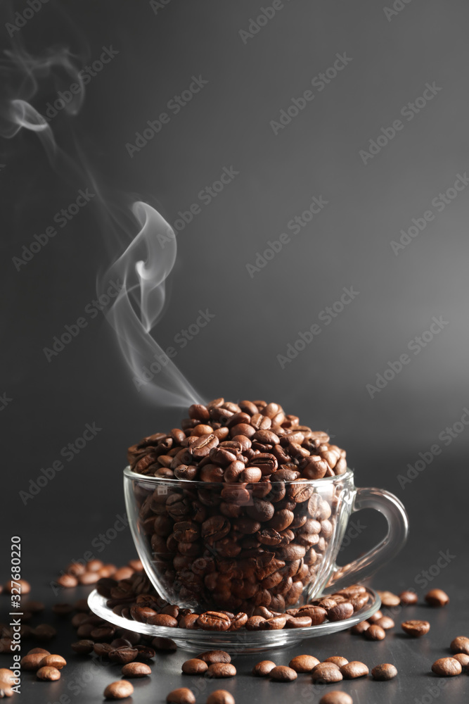 Cup with coffee beans on dark background