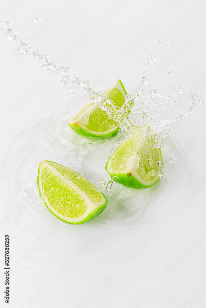 Splash of water and fresh cut lime against white background