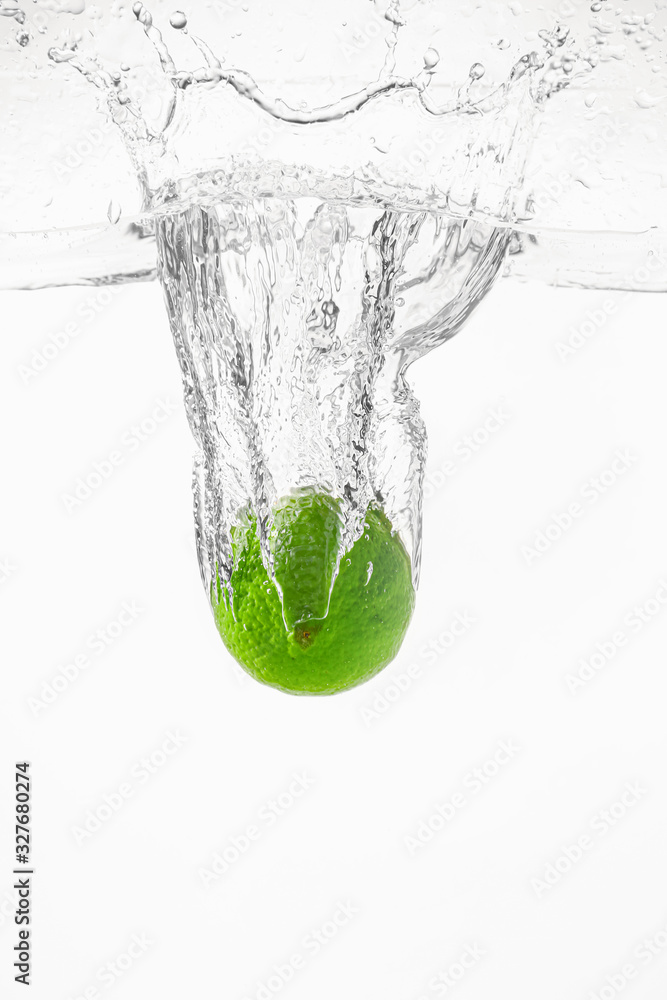 Falling of fresh lime into water against white background