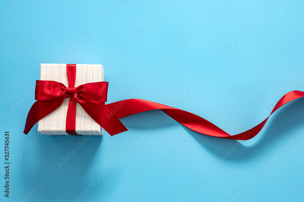  gift box with red bow on a blue background . Happy Fathers or Mothers or Women s  day celebratio