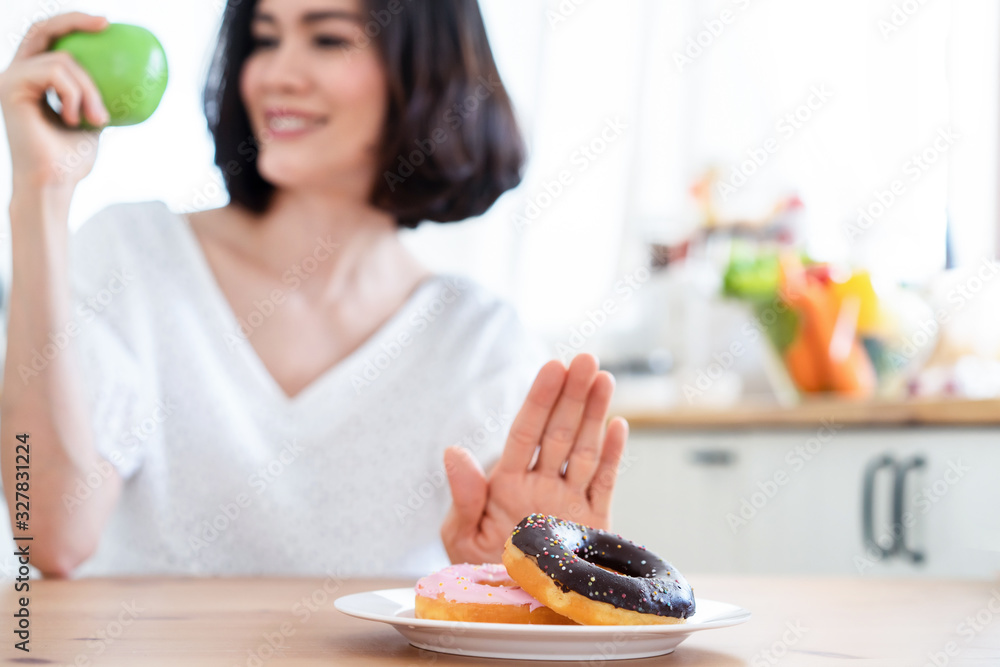 年轻女孩拒绝垃圾食品或甜甜圈等不健康食品，选择a等健康食品