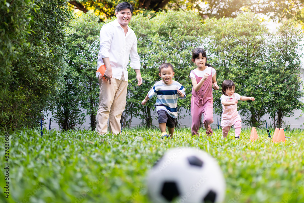 Asian big family playing in garden playground at home together. Children running to kick and catch f