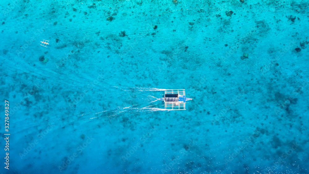 Aerial top down view of boat moving in open sea with clear and turquoise water on over coral reef,  