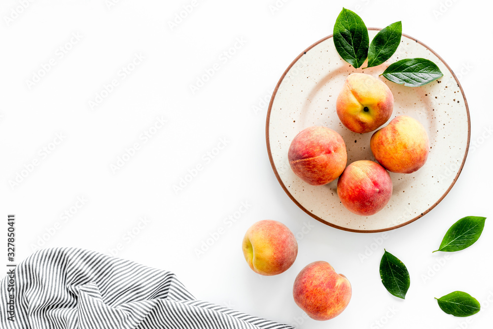 Summer lunch. Red peaches on white background with tablecloth and leaves top-down copy space