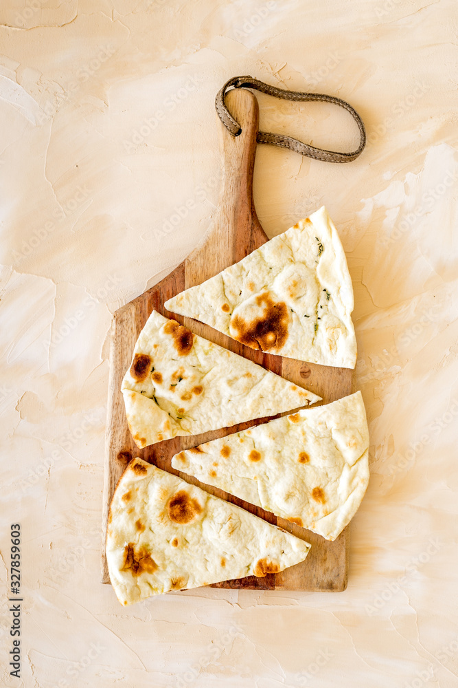 制作focaccia。传统的意大利面包放在米色桌子上的砧板上自上而下