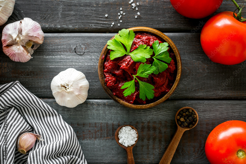 Homemade tomato sause near ingredients - garlic, spices - on dark wooden background top-down