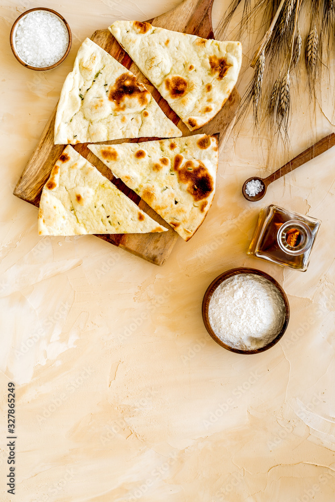 Focaccia ingredients. Wheat ears, flour, oil near bread on beige background top-down copy space