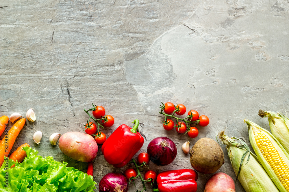 Set of autumn vegetables - potato, cucumber, carrot, greenery - on grey background top-down copy spa