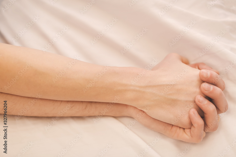 Hands of young couple sleeping in bed