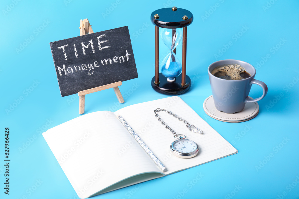 Notebook, hourglass, cup of coffee and clock on color background. Time management concept