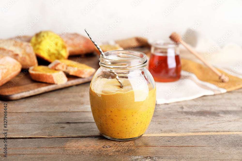 Jar of tasty honey mustard sauce on wooden table