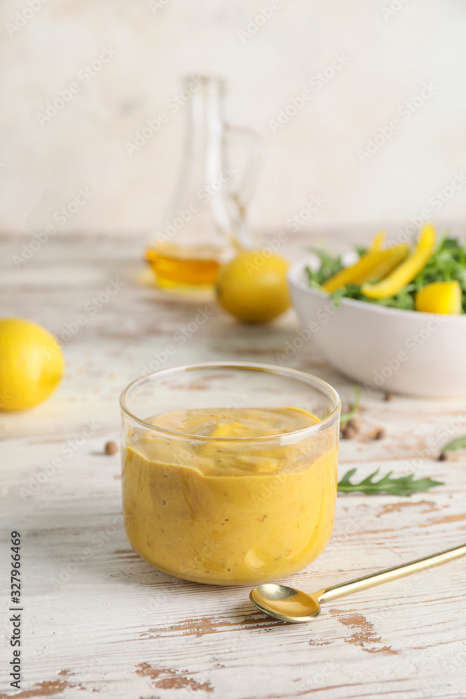 Glass of tasty honey mustard sauce on white wooden table