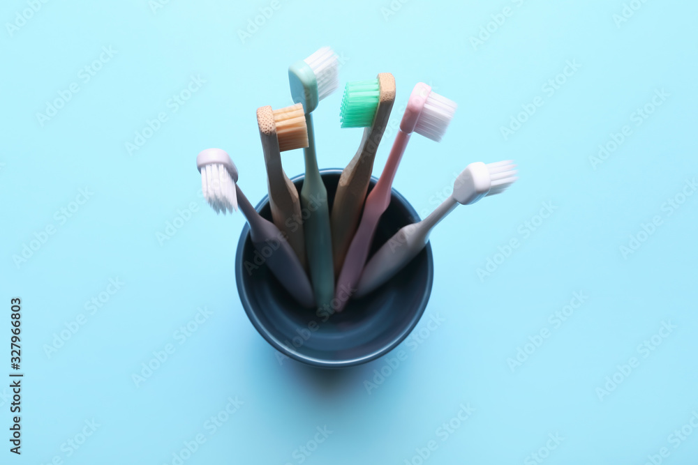 Many tooth brushes in holder on color background