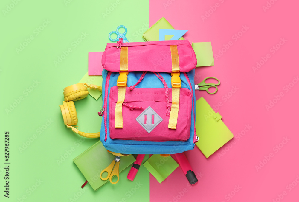 School backpack and stationery on color background