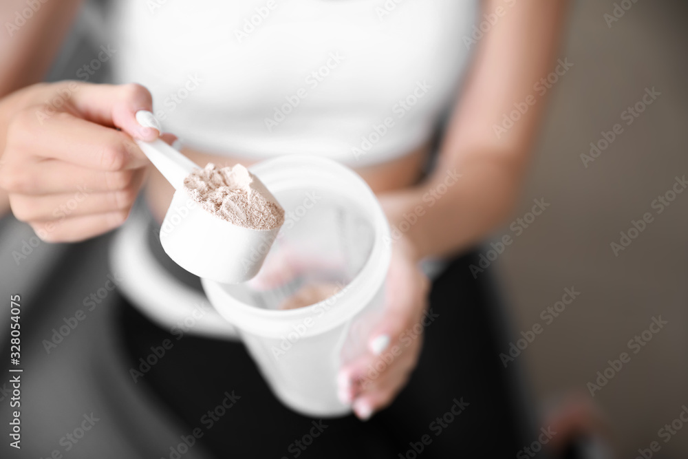 Sporty young woman with protein at home, closeup