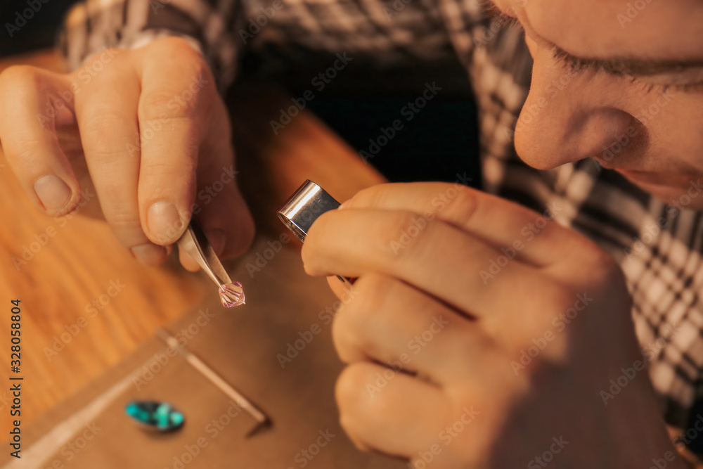 Jeweler examining gemstone in workshop, closeup