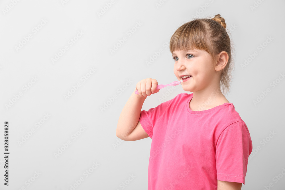 Little girl with tooth brush on light background