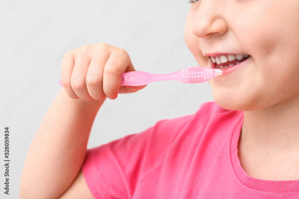 Little girl with tooth brush on light background, closeup