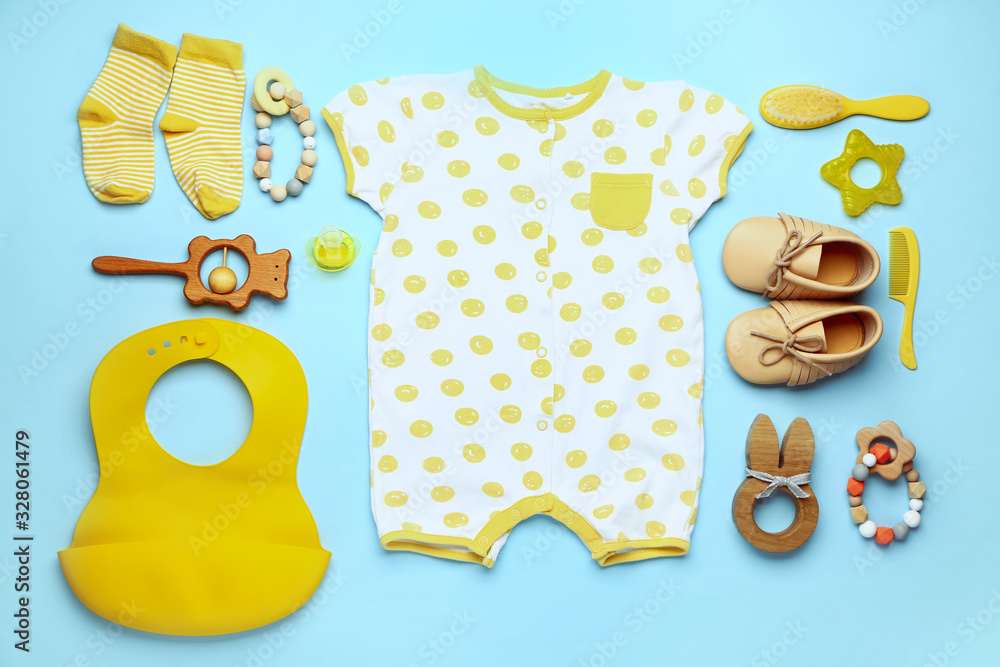 Baby clothes and accessories on color background